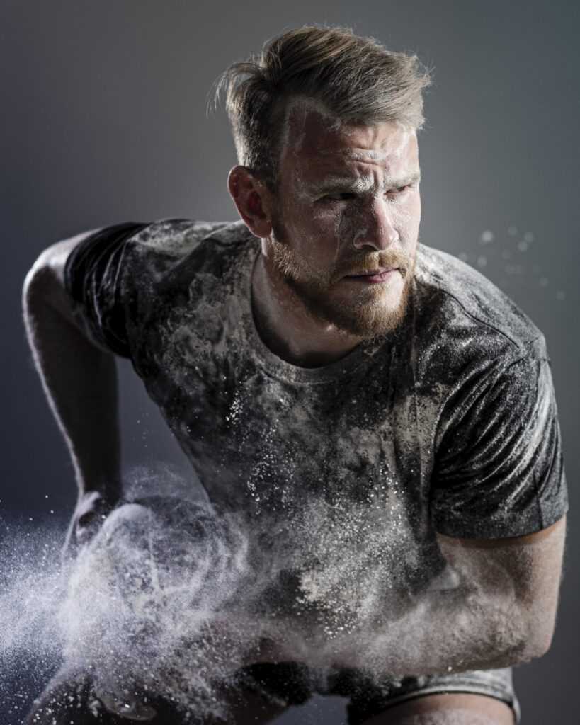 front-view-athletic-male-rugby-player-holding-ball-with-dust