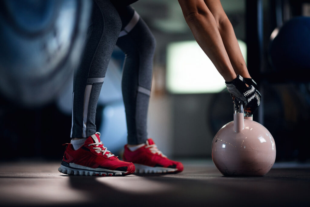 Unrecognizable athlete exercising with kettle bell on sport training in a gym.